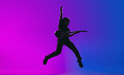 Jumping. Silhouette of young Caucasian girl, female guitarist playing isolated over gradient blue-pink background in neon light. Concept of music, art, human emotions. Copy space for ad.